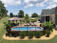 an above ground pool surrounded by grass and trees with a gazebo in the middle