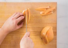 a person cutting up orange slices on a wooden board