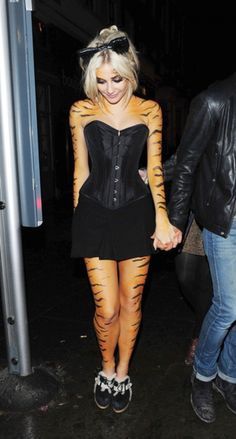 a woman dressed as a tiger is holding hands with a man in a leather jacket