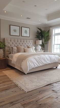 a large white bed sitting in the middle of a bedroom next to a window on top of a hard wood floor