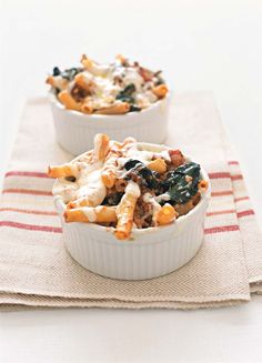 two bowls filled with pasta and vegetables on top of a tablecloth covered placemat