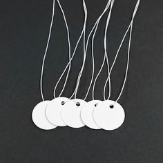 three white tags hanging from strings on a black surface