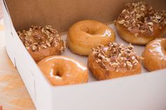 six glazed donuts with nuts in a box