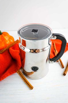 a coffee mug with cinnamon sticks next to it and an orange blanket in the background