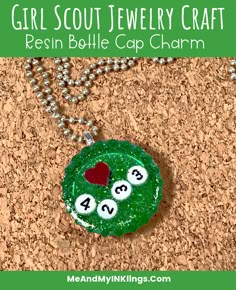 a close up of a necklace on a cork background with the words girl scout jewelry craft