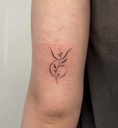 a woman's arm with a small flower tattoo on the back of her left arm