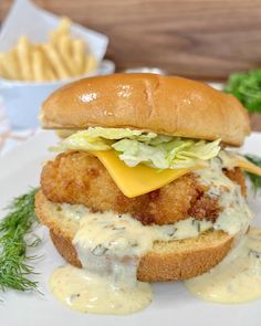 a chicken sandwich with cheese and lettuce on a white plate