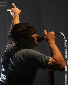 a man singing into a microphone while holding his hand up in the air with both hands