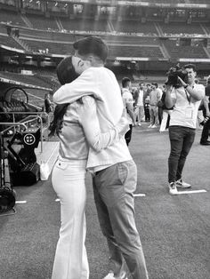 a man and woman hug in front of an empty stadium