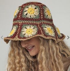 a woman wearing a crocheted hat with flowers on the brim and long curly hair