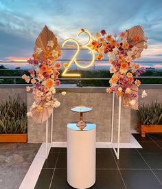 two tall white vases with flowers on them near a sign that reads twenty and twenty