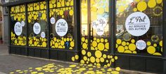 a storefront with yellow circles painted on the windows and in front of it is a sidewalk