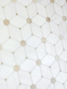 an image of a bathroom scene with focus on the toilet and tile flooring that looks like hexagonal tiles