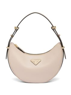 Find PRADA Arqué Leather Shoulder Bag on Editorialist. This Prada shoulder bag is crafted from beige leather with a smoothing finish. It features an enamel triangle logo, adjustable shoulder strap, adjustable detachable shoulder strap, top zip fastening, internal slip pocket, internal logo stamp, leather lining, and gold-tone hardware. The bag has a curve-edge body. Prada Arque Bag, Beige Bags, Luxury Bags Collection, Beige Bag, Designer Shoulder Bags, Girly Bags, Girly Accessories, Iconic Bags, Van Cleef Arpels