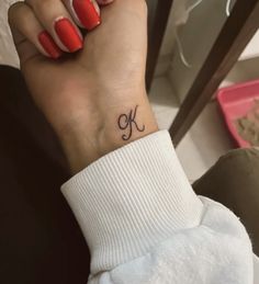 a woman's wrist tattoo with the letter k on it