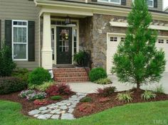 a house with landscaping in front of it and stone steps leading to the front door