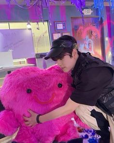 a man is hugging a large pink teddy bear