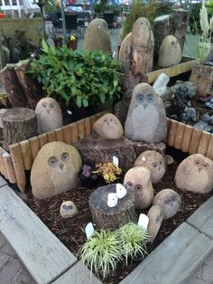 some rocks and plants in a planter on the side of the road with faces carved into them