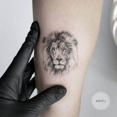 a lion tattoo on the left thigh and right leg with black gloves holding it up