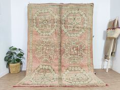 an antique rug is displayed on the floor next to a potted plant