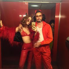 a man and woman dressed up in devil costumes taking a selfie with a cell phone