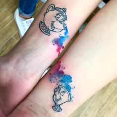 two people with matching disney tattoos on their arms and feet, both have faces painted in blue and red ink