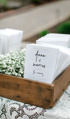 a wooden box filled with white cards and baby's breath flowers on top of a table