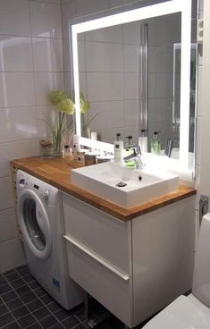 a washer and dryer in a bathroom with a mirror over the sink above it