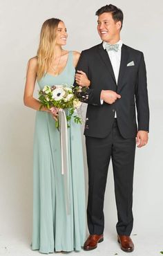 a man in a tuxedo standing next to a woman in a long dress