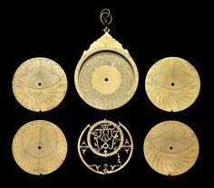 four pieces of gold metal with designs on them and an arrow hanging from the middle