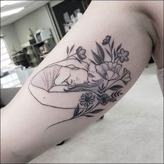 a woman's arm with flowers and leaves on it