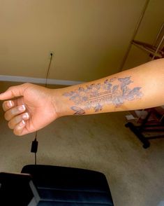 a person's arm with a tattoo on it and a suitcase in the background