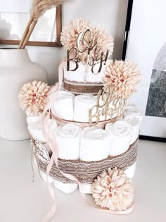 a three tiered diaper cake is adorned with pink flowers and monogrammed letters