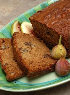 slices of banana bread on a green and white plate with an apple, two pieces of garlic