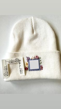 a white beanie with flowers on it and a photo frame attached to the front