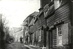 an old black and white photo of people walking down the street in front of houses