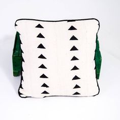 a white and green pillow with black triangles on the front, sitting on a white surface