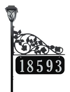 a black and white street sign with flowers on it's side next to a lamp post