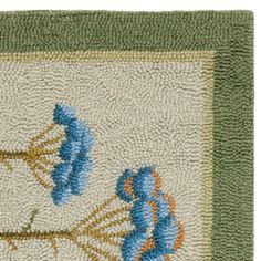 a rug with blue flowers on it and green border around the edges, in front of a white background