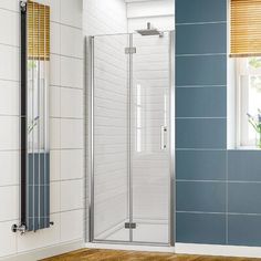 a bathroom with a wooden floor and blue tile on the walls, along with a walk in shower