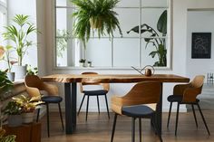 a dining room table with four chairs and a potted plant in the window sill