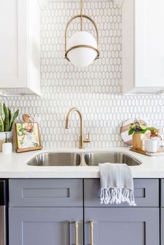 a kitchen with white cabinets and gold faucet lighting over the sink, along with potted cacti