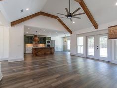 an empty living room with wood flooring and ceiling fan in the middle of it