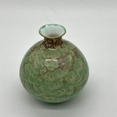 a green vase sitting on top of a white table