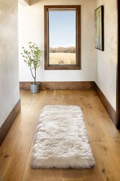 a large white rug sitting on top of a hard wood floor next to a window