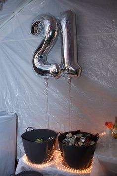 two buckets filled with money are next to a balloon shaped like the number twenty