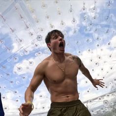 a shirtless man with his mouth wide open standing in front of bubble like balls