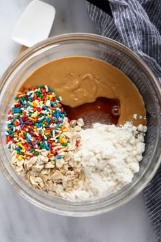 the ingredients for peanut butter, sprinkles, and oatmeal in a glass bowl