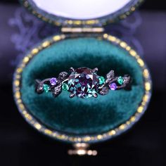 a ring with purple and green stones in a velvet box