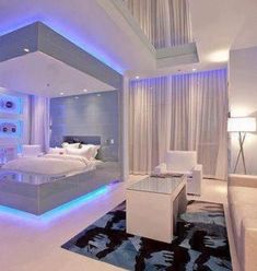 a modern bedroom with white furniture and blue lights on the walls, along with a large bed